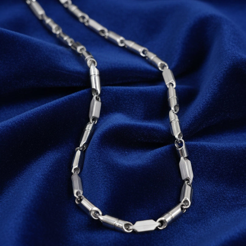 Silver chain necklace on a blue fabric background