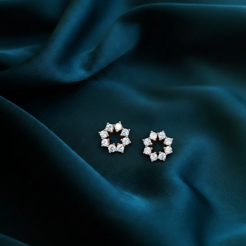 Pair of diamond earrings on a dark teal fabric