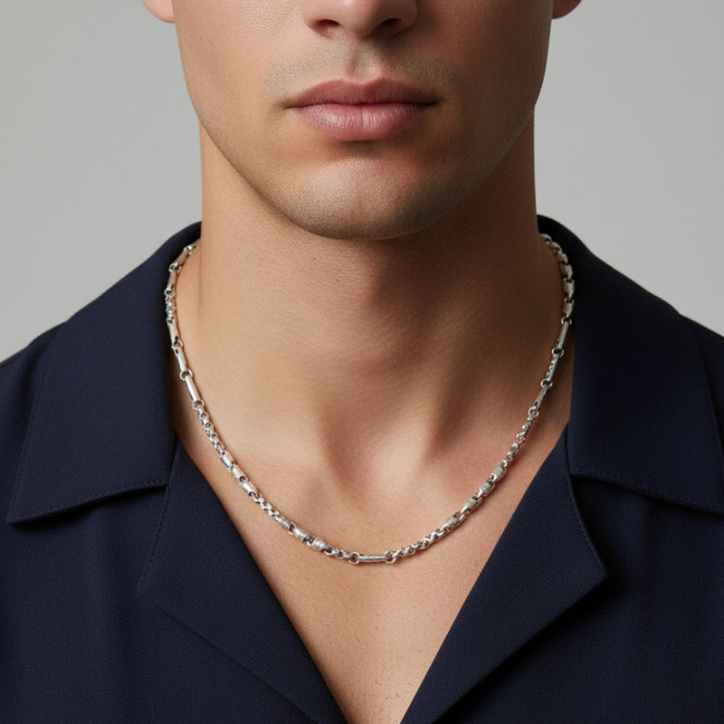 Man wearing a silver necklace against a neutral background